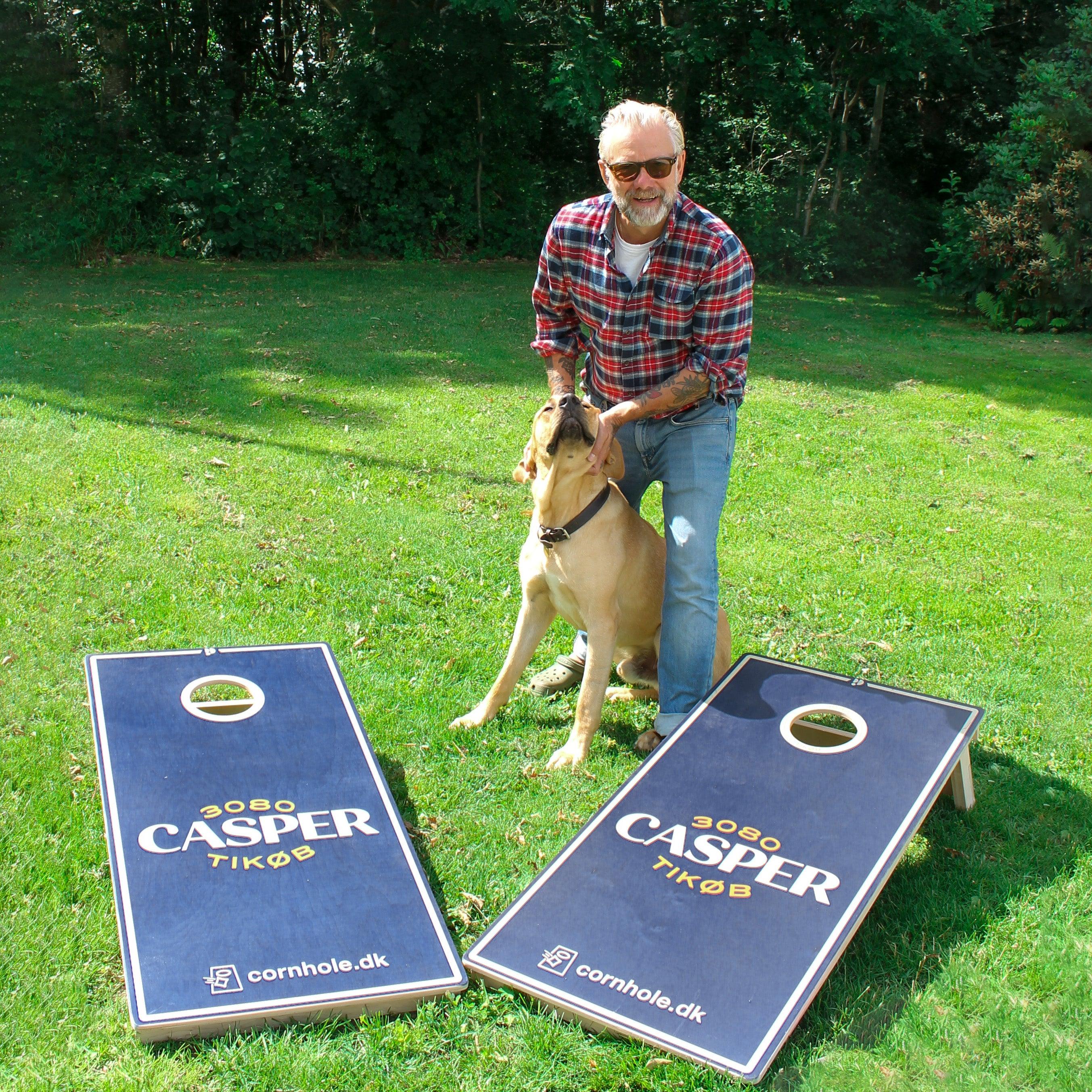 Casper Christensen står med 2 premium custom cornholesæt fra cornhole.dk sammen med hans hund